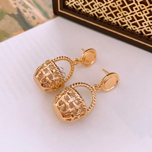 Macro view of gold woven basket earrings with white pearls and polished studs