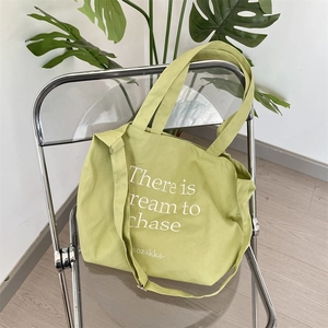 Detail of avocado green canvas tote bag with adjustable strap and chic letter print