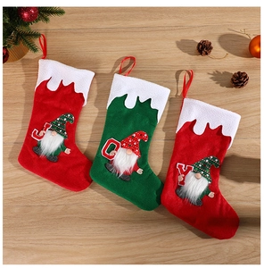 Détail de trois chaussettes de Noël avec des gnomes JOY sur un sol en bois rustique