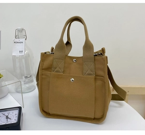 Brown canvas tote bag detail with snap button pocket and adjustable shoulder strap