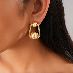Primer plano de los pendientes de esfera chapados en oro 18K con textura en una modelo