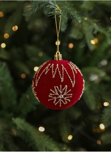 Detail of red velvet Christmas ball with gold embroidery and beads hanging on a tree