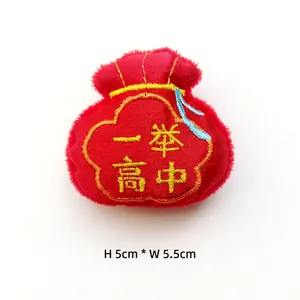 Dettaglio di un sacchetto in peluche rosso con ricamo dorato e dimensioni 5x5,5 cm