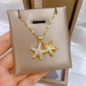Close-up of golden starfish pendant necklace with cubic zirconia and a white pearl