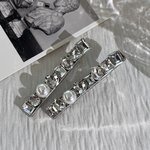 Detailed macro shot of silver hair clips with sparkling crystals and elegant white pearls