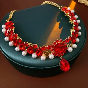 Macro view of vintage gold necklace with red gemstones and pearl droplet detail