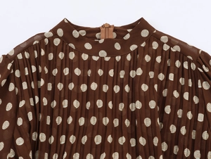 Detail of polka dot pleated dress neckline featuring brown fabric and hidden back zipper
