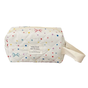 Quilted makeup bag with colorful polka dots and bow patterns featuring top handle