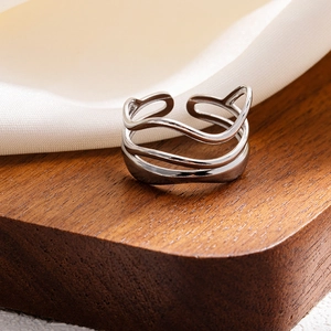 Detail of silver multilayer wave ring with polished finish on a wooden stand