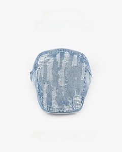 Close-up of light blue distressed denim beret featuring vintage frayed hole details
