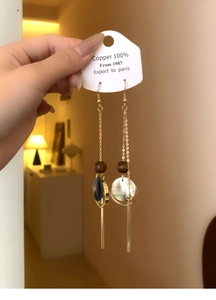 Detail of vintage long drop earrings with wood beads, black shell, and gold-tone tassels