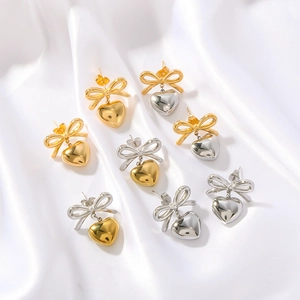 Titanium bow knot heart earrings in gold and silver finish on white silk background