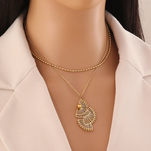 Gros plan d'un collier doré à plusieurs rangs avec pendentif élégant en feuille de ginkgo