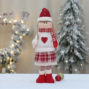 Detail of Christmas girl doll featuring a red hat, knit sweater, and plaid lace skirt