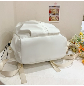 Close-up of the breathable back panel and drawstring base of this white nylon backpack