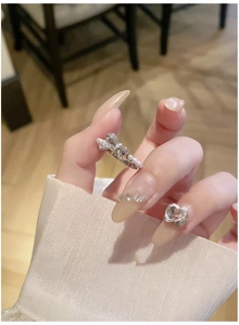 Detail of silver bow ring with white pearls and zircons on a model's finger