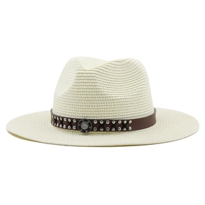 Detail of beige woven straw cowboy hat featuring brown leather band with silver studs