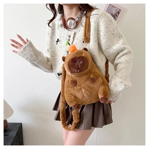 Cute capybara plush crossbody bag with orange detail worn by a model in a natural setting
