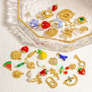 Détail de breloques dorées 18K incluant fraises, étoiles de mer et perles en émail