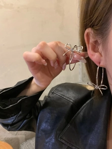 Close-up of a silver bow hoop earring worn by a model in black leather jacket