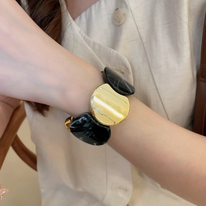Détail du bracelet élastique large en métal doré poli et résine effet marbre noir