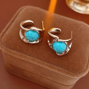 Close-up of vintage gold earrings with textured turquoise stones on brown velvet