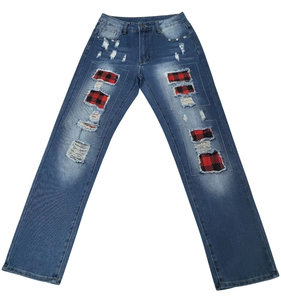 Détail du jean bleu foncé avec des trous déchirés et des patchs en tissu à carreaux rouges