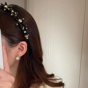 Detailed close-up of a black floral headband with crystals and white rose earrings