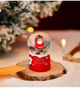 Close-up of red base Christmas snow globe with Santa Claus inside on wooden slice