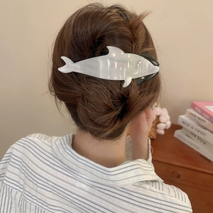 Rear view of a pearlescent white whale hair claw clip styled in a minimalist bun hairstyle