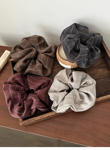 Set of four striped fabric scrunchies in autumn tones on a vintage wooden tray