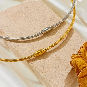 Elegant gold and silver snake chain necklaces draped on stone with silk background