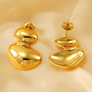 Irregular geometric gold stainless steel earrings on elegant warm silk fabric