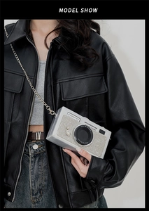 Macro view of camera-shaped clutch bag featuring sparkling rhinestones and metal chain