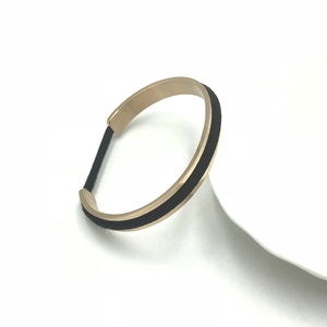 Detail of a C-shaped gold metal bracelet with a functional groove for hair tie storage