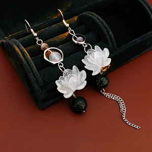 Detailed shot of asymmetric lotus earrings with white petals and black beads