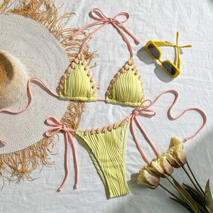 Detailed flat lay of a yellow ribbed bikini set with pink halter ties and metal eyelets