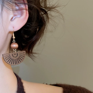 Gros plan de boucles d'oreilles ethniques en bois en forme d'éventail portées sur l'oreille