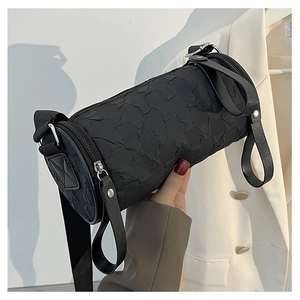 Detailed view of the black pleated cylindrical bag featuring a textured finish and strap