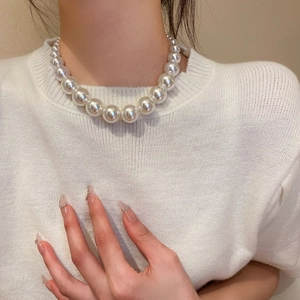 Close-up of elegant gradient pearl necklace on a model wearing white knitwear
