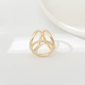 Macro shot of minimalist triple-intertwined gold ring on a white ceramic tray