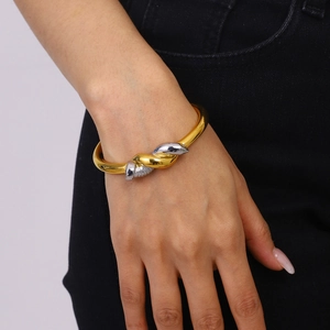 Polished 18k gold and silver dual-tone twisted knot stainless steel cuff bangle on wrist