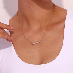 Détail d'un collier plaqué or minimaliste avec un pendentif rectangulaire en nacre sur modèle