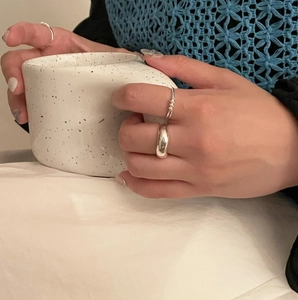 Detail of minimalist 925 sterling silver knot rings on hand holding a ceramic cup