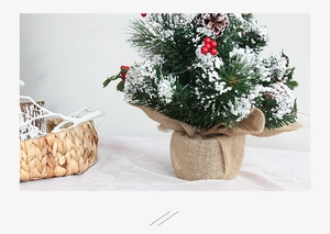 Detail of snowy mini Christmas tree with red berries, pine cones and burlap base