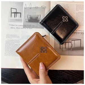 Detailed stitching and clover metal clasp on minimalist black and brown short purses