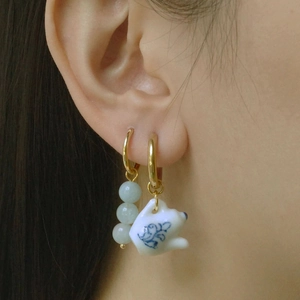 Detail view of asymmetric blue and white porcelain teapot earrings with jade green beads
