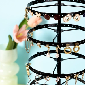 Detailed macro view of a black rotating earring stand with multi-layered jewelry storage