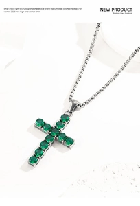 Detailed close-up of a silver titanium steel cross pendant with an emerald green gemstone