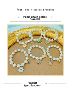 Detail of beaded pearl bracelets with gold charms like evil eye, turtle and heart motifs